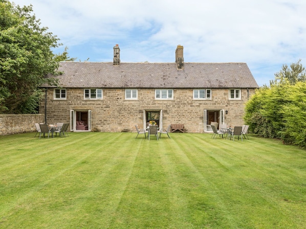 A stone building with a large lawn and outdoor seating area.