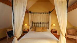 A four-poster canopy bed with white bedding and two bedside lamps. - The Granary (Shrewsbury)