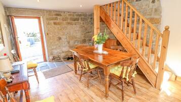 A dining area with a wooden table and chairs, a potted plant, and a staircase leading to an upper level.
