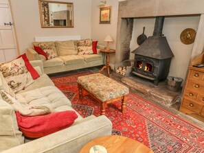 A cozy living room with a sofa, ottoman, and a fireplace.