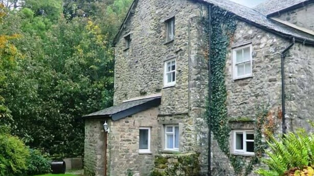 A stone building with a gravel driveway and a small garden area. - Beckside Cottage (Carnforth)