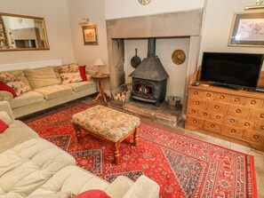 A cozy living room with a stone fireplace, a sofa, a television, and a patterned rug.