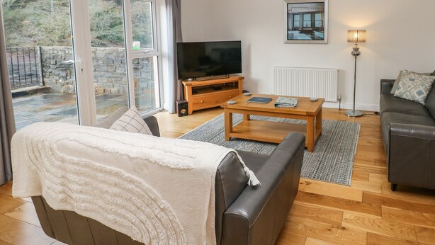 A living room with a sofa, a coffee table, a TV, and a lamp. - Curlew (Milford Haven)