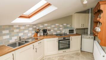 A compact kitchen with a skylight, a microwave, an oven, and a coffee maker.