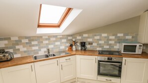 A kitchen with a skylight, a microwave, an oven, and a coffee maker. - Foxglove Cottage (Haverfordwest)