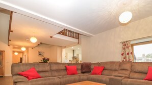 A spacious living room with a large sectional sofa, a wooden coffee table, and a staircase leading to an upper level.