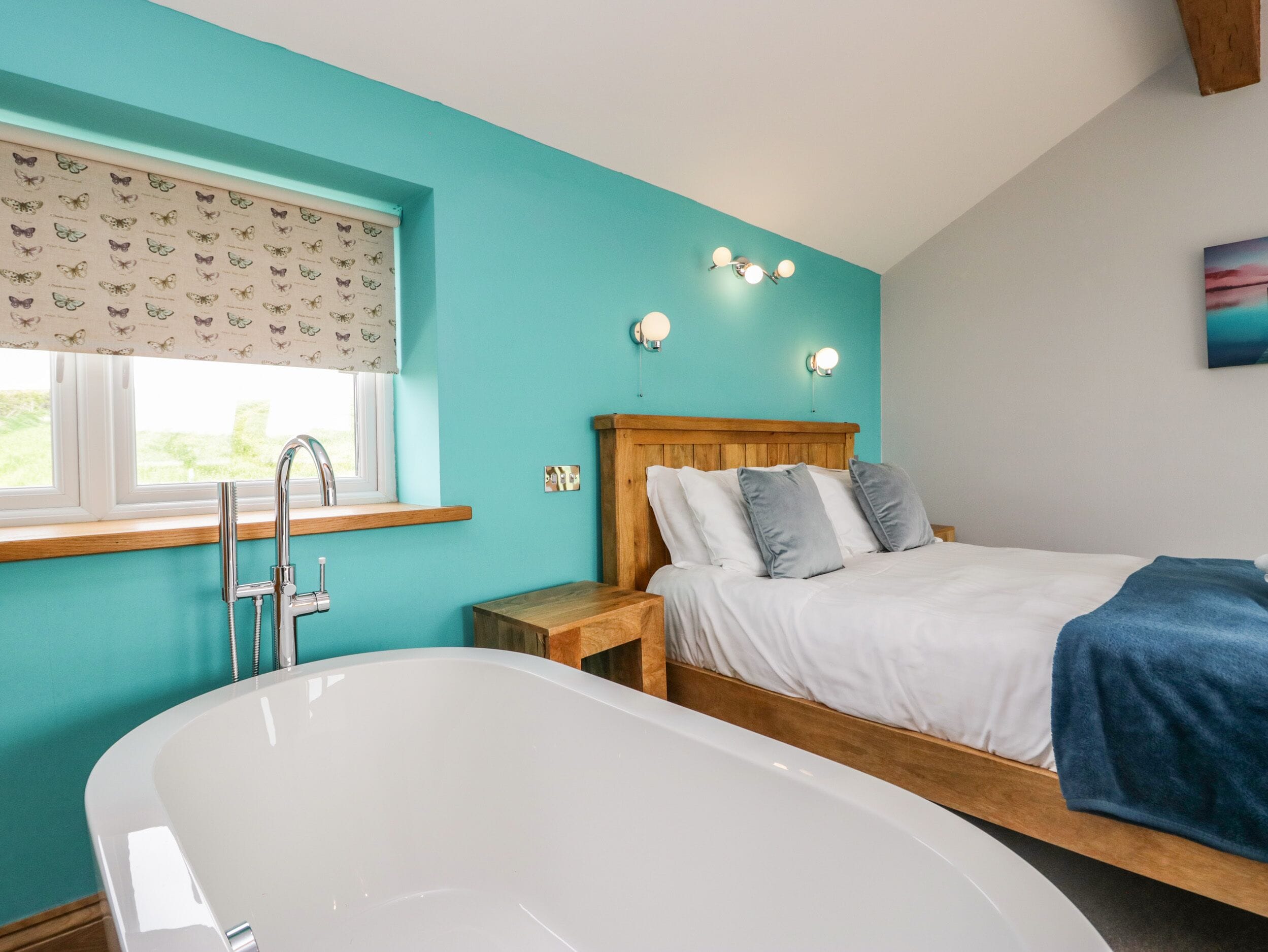 A bedroom with a large bathtub, a wooden headboard, and a window with butterfly-patterned curtains.