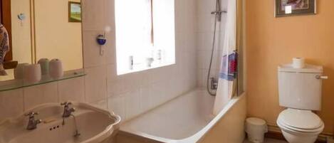 A bathroom with a bathtub, sink, toilet, and a window.
