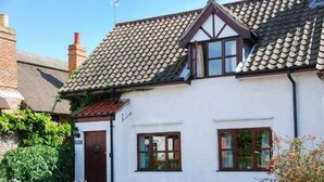 A white house with a tiled roof, wooden windows, and a wooden fence. - Kingsley Cottage (Norwich)