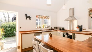 Una cocina moderna con una isla de madera, muebles blancos y electrodomésticos de acero inoxidable.