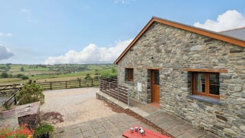 A stone building with a red bench and a view of the countryside.