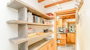 A kitchen with wooden cabinets, a stone countertop, and a hanging light fixture. - Mill Cottage (Hawes)