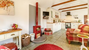 A cozy living room with a fireplace, a dining area, and a kitchen. - Willow Cottage (Driffield)