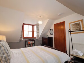 A bedroom with a bed, a window, a bookshelf, a door, and a framed picture on the wall. - Seascape (Buckie)