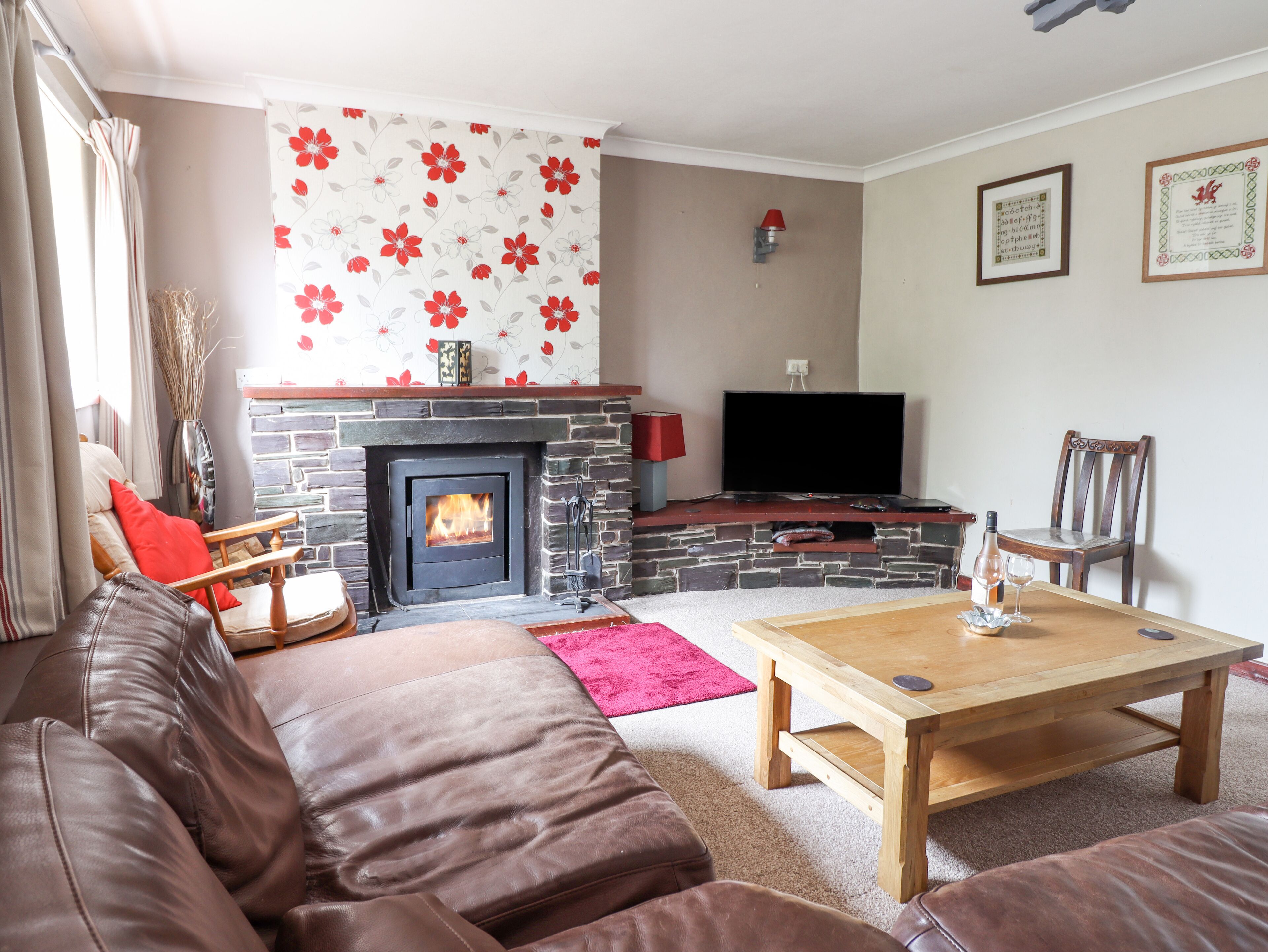 A living room with a stone fireplace, a television, a wooden coffee table, and a brown leather sofa.
