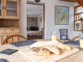 A dining table with croissants and a glass of orange juice.