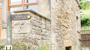 Un bâtiment en pierre sur lequel est apposée une pancarte indiquant un sentier menant à la ferme de Kelbrick.
