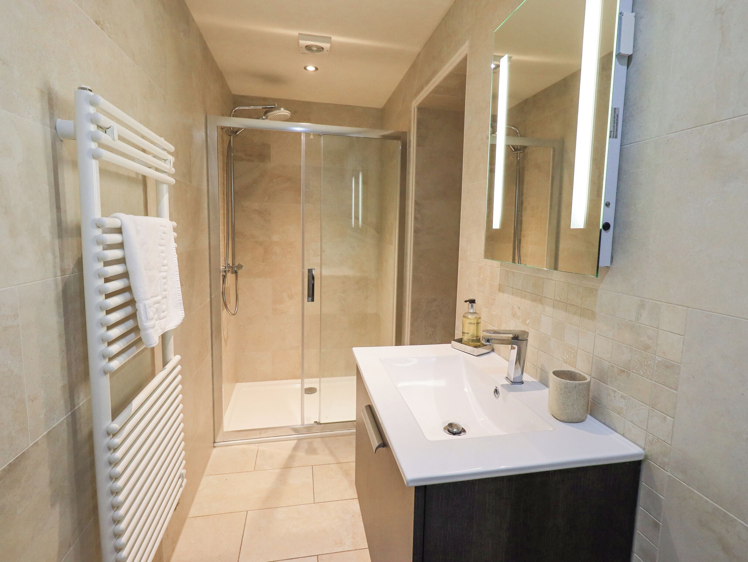 A modern bathroom with a glass shower enclosure, a white sink, and a large mirror.
