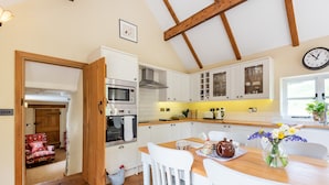 A kitchen with white cabinets, a wooden ceiling, and a dining table with chairs.