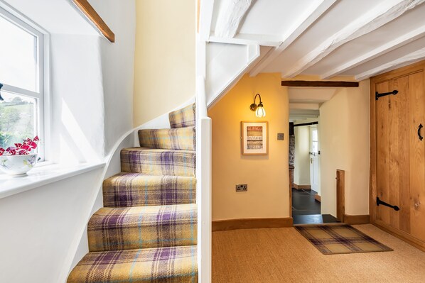 A staircase with a plaid carpet, a wall-mounted light fixture, and a wooden door. - Pen Y Bont (Llangollen)