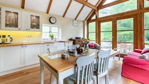 A spacious kitchen with wooden beams, a dining area with a wooden table, and a red sofa.