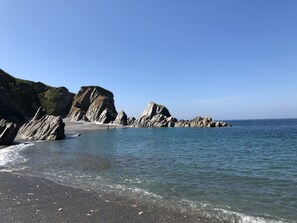 Een kustlandschap met rotskliffen en een strand.