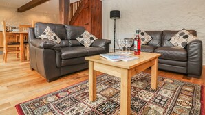 A cozy living room with two leather sofas, a wooden coffee table, and a patterned rug. - The Cider Barn (Newton Abbot)