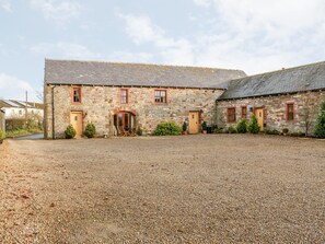 A stone building with a gravel driveway and a small patio area with outdoor furniture.