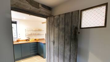 Uma cozinha com armários azul escuro, uma porta de madeira e uma janela com vidro estampado.