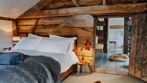 A rustic wooden bedroom with a bed, a lamp, and a cowhide rug. - The Hayloft (Ross-on-Wye)