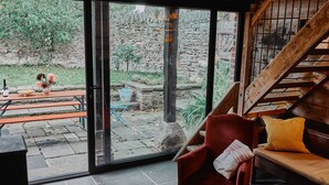 A room with a glass door leading to an outdoor area with stone walls and a wooden staircase. - The Hayloft (Ross-on-Wye)