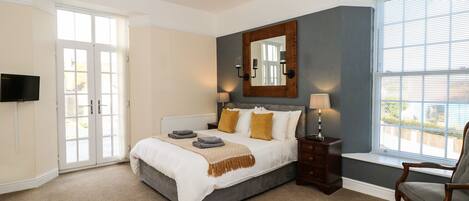 A bedroom with a bed, bedside tables, a mirror, and a window.