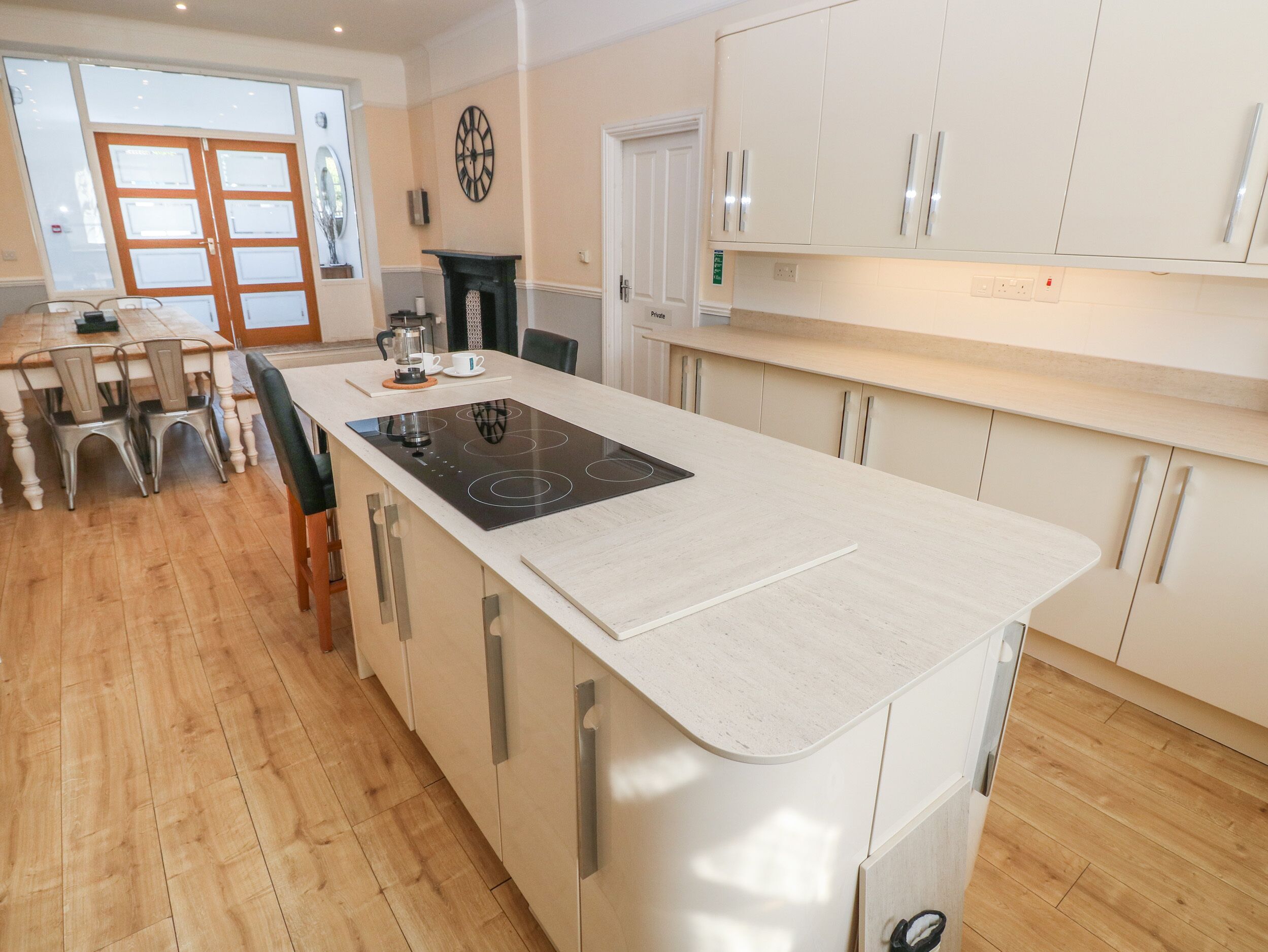Una cocina moderna con una isla central, suelo de madera y armarios blancos.