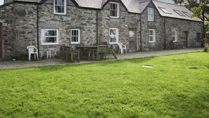 A stone building with multiple windows and a grassy lawn in front. - Bryn Dedwydd Farmhouse (Betws-Y-Coed)