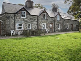 A stone building with multiple windows and a grassy lawn in front.