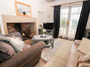 Cozy living room with a fireplace, comfortable seating, and a television, offering a view of the outdoors.
