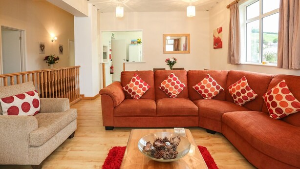 A living room with a sofa set, a coffee table, and a red rug. - The Cabin (Ilfracombe)