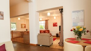 A spacious living area with a sofa, a dining table with chairs, and a kitchen in the background. - The Cabin (Ilfracombe)