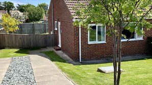 A brick house with a tiled roof, a front yard with a tree, and a wooden fence. - Araucaria House (Whitby)