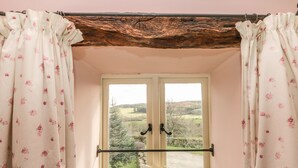 Une pièce avec un plafond en bois, une porte blanche dotée de panneaux de verre et une vue sur un paysage verdoyant.