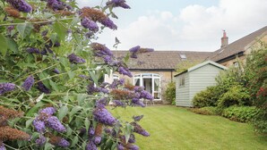 Een huis met een verzorgd gazon en een tuin met paarse bloemen.