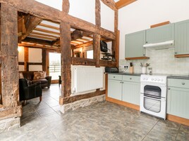 Una cocina rústica con vigas de madera a la vista, chimenea de piedra y vistas al exterior.