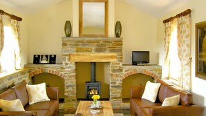 A cozy living room with a stone fireplace, leather sofas, and a television. - Valley View (Ross-on-Wye)