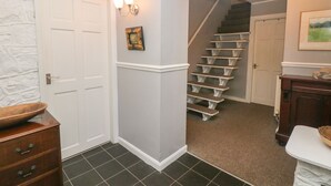 A hallway with a white door, a staircase, and a small framed picture on the wall. - The Old Barn (Stoke-on-Trent)