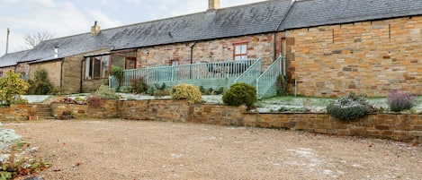 A stone building with a gravel driveway and a small garden area.