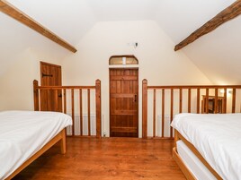 Un dormitorio con dos camas de madera, una puerta de madera y un techo blanco.