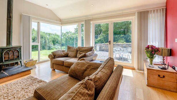 Amplia sala de estar con un sofá grande, chimenea y ventanas amplias que ofrecen vistas al exterior.