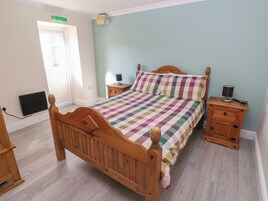 Un dormitorio con una cama de madera, una mesita de noche y un radiador, además de una ventana.