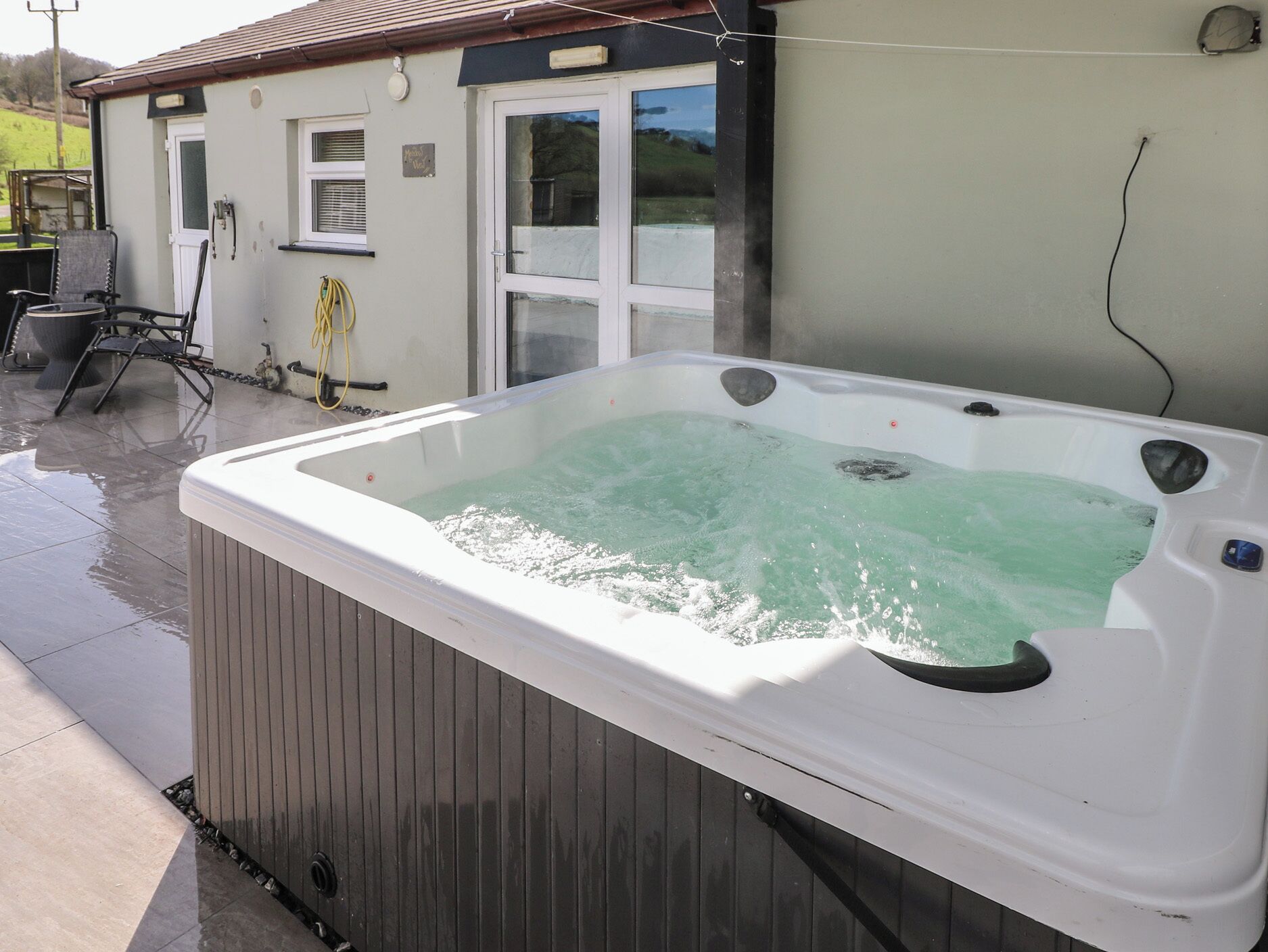 Un bain à remous installé à l’extérieur, avec une maison en arrière-plan.