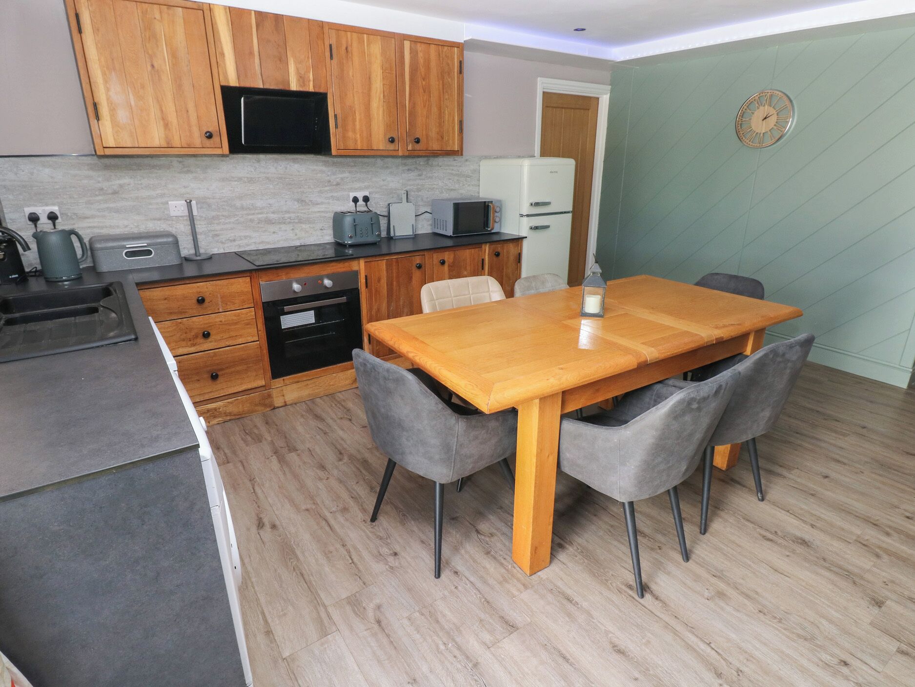 A compact kitchen with wooden cabinets, a built-in microwave, a toaster, and a refrigerator.